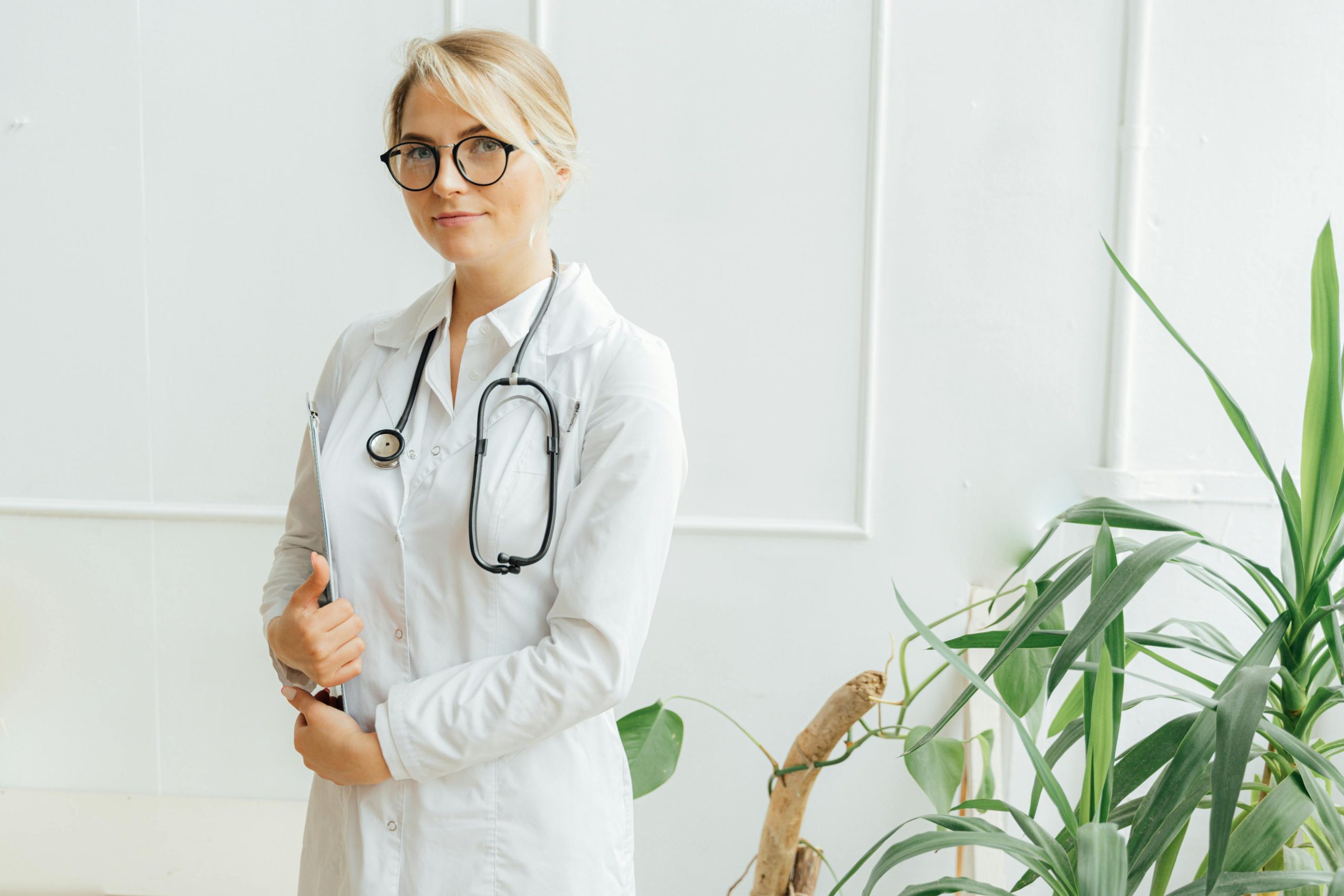 Confident female doctor standing with stethoscope in a bright clinic setting.