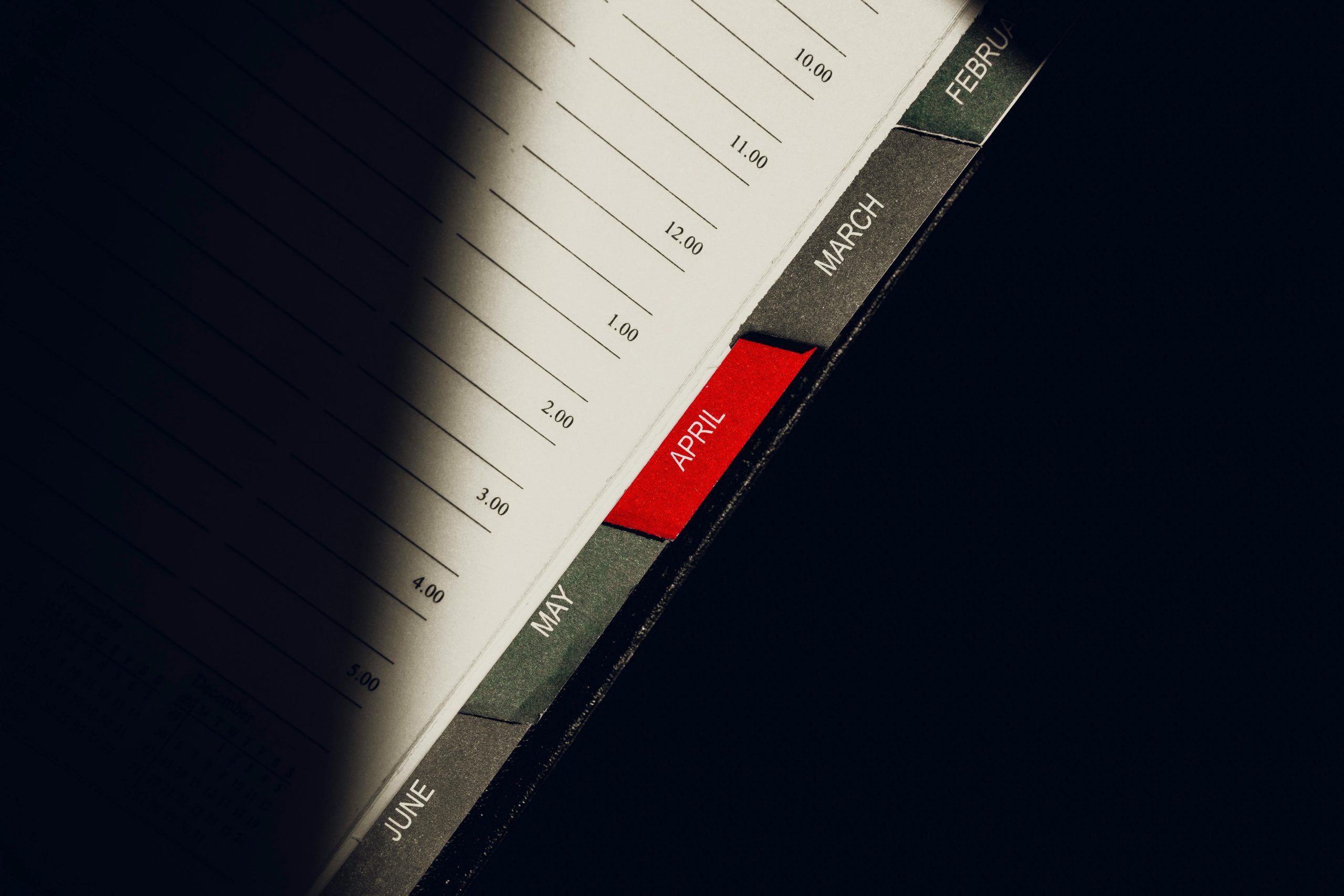 A close-up shot of a planner highlighting the month of April with visible monthly tabs.